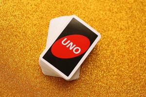 TERNOPIL, UKRAINE - MAY 15, 2022 Many colorful UNO game cards on golden background. UNO is an American shedding-type card game that is played with a specially printed deck photo