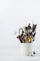 Set of cutlery of spoons, knives and forks in cup with holiday decorations on dining table, copy space photo