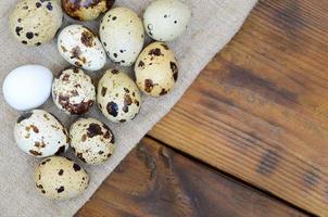 Quail eggs on sacking on a dark brown wooden surface, top view, empty place for text, recipe photo