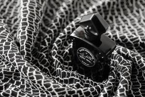 TERNOPIL, UKRAINE - SEPTEMBER 2, 2022 Black Perfecto La Petite Robe Noire by Guerlain perfume bottle on plaid in monochrome colors photo