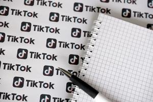 ternopil, ucrania - 2 de mayo de 2022 bloc de notas con bolígrafo y muchos logotipos de tiktok impresos en papel. tiktok o douyin es un famoso servicio chino de alojamiento de videos de formato corto propiedad de bytedance foto