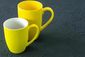 Two yellow cups on gray background. Color of the year 2021. photo