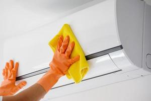 Asian man cleaning air conditioner with microfiber cloth photo