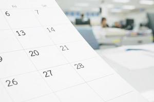 Close up white paper desk calendar on table with blurred office interior background photo