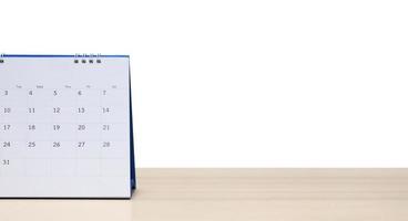 Calendario de escritorio blanco en la parte superior de la mesa de madera aislado sobre fondo blanco. foto