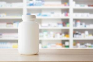 White medicine bottle on wood counter with pharmacy drugstore shelves blur pharmaceutical background photo