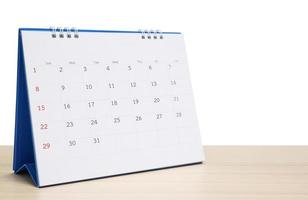 White desk calendar on wood table top isolated on white background photo