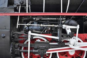 ruedas de la vieja locomotora de vapor negra de la época soviética. el lado de la locomotora con elementos de la tecnología giratoria de trenes antiguos foto