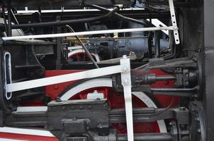Wheels of the old black steam locomotive of Soviet times. The side of the locomotive with elements of the rotating technology of old trains photo