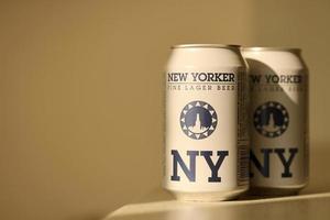 TERNOPIL, UKRAINE - JULY 18, 2022 Two cans of New Yorker fine lager beer with original logo and design on brown retro background photo