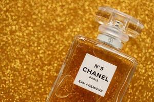 TERNOPIL, UKRAINE - SEPTEMBER 2, 2022 Chanel Number 5 Eau Premiere worldwide famous french perfume bottle on shiny glitter background in purple colors photo