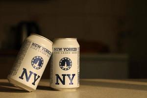 TERNOPIL, UKRAINE - JULY 18, 2022 Two cans of New Yorker fine lager beer with original logo and design on brown retro background photo