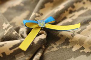 TERNOPIL, UKRAINE - SEPTEMBER 2, 2022 Ribbon with Ukrainian Coat of Arms and national flag colors on army camouflage uniform photo