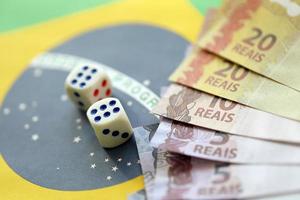 cubos de dados con billetes de dinero brasileño en la bandera de la república de brasil. concepto de suerte y juego en brasil foto