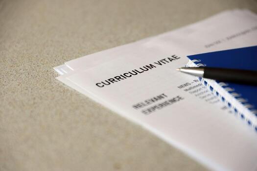 Top view of stack of office documents including resume and cv forms on the desk close to pen and notepad. Job seeking process. Hunting for workplace photo