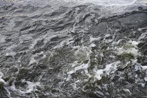 Waves of water of the river and the sea meet each other during high tide and low tide. Deep blue stormy sea water surface with white foam and waves pattern, background photo