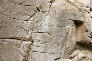 Light coarse natural rock stone background. Mining cliff rough front surface. Big limestone stack backdrop. Heavy grunge damaged granite block texture photo