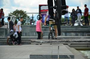 A cyclist jumps over a pipe on a BMX bike. A lot of people with bicycles in the background. Extreme sports concept photo