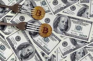 Bitcoin getting New Hard Fork Change, Physical Golden Crytocurrency Coin under the fork on the dollars background. Blockchain Transaction System Crisis Concept photo