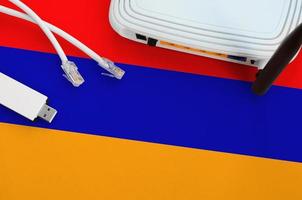 Armenia flag depicted on table with internet rj45 cable, wireless usb wifi adapter and router. Internet connection concept photo