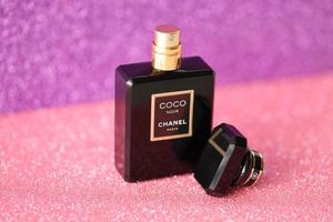 TERNOPIL, UKRAINE - SEPTEMBER 2, 2022 Coco Noir Chanel Paris worldwide famous french perfume black bottle on shiny glitter background in purple colors photo