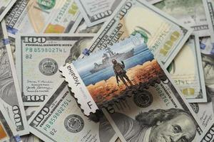 TERNOPIL, UKRAINE - SEPTEMBER 2, 2022 Famous Ukrainian postmark with russian warship and ukrainian soldier as wooden souvenir on big amount of US dollar bills photo