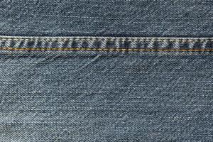 Detailed abstract texture of dark blue denim cloth. Background image of old used denim trousers fabric photo