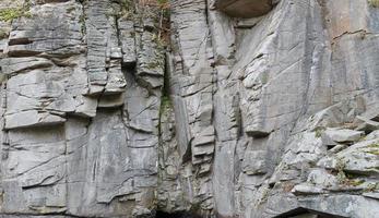 Light coarse natural rock stone background. Mining cliff rough front surface. Big limestone stack backdrop. Heavy grunge damaged granite block texture photo