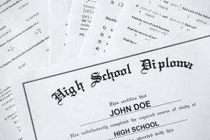 High School Diploma copy lies on many pages of alghebra and geometry tests and tasks. Graduation document photo