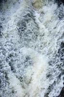 Waves of water of the river and the sea meet each other during high tide and low tide. Deep blue stormy sea water surface with white foam and waves pattern, background photo