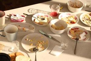 platos sucios vacíos con cucharas y tenedores en la mesa después de la comida. concepto de final de banquete. platos sin lavar foto