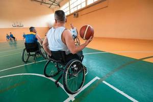 Disabled War veterans mixed race and age basketball teams in wheelchairs playing a training match in a sports gym hall. Handicapped people rehabilitation and inclusion concept photo