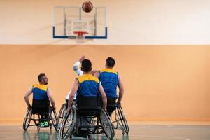 Disabled War veterans mixed race and age basketball teams in wheelchairs playing a training match in a sports gym hall. Handicapped people rehabilitation and inclusion concept photo