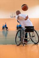 Disabled War veterans mixed race and age basketball teams in wheelchairs playing a training match in a sports gym hall. Handicapped people rehabilitation and inclusion concept photo