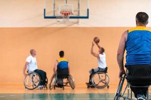 Disabled War veterans mixed race and age basketball teams in wheelchairs playing a training match in a sports gym hall. Handicapped people rehabilitation and inclusion concept photo