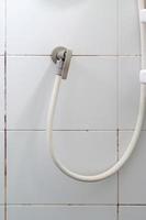The white rubber strap with the brass faucet of the shower. photo