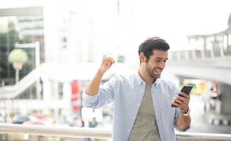The young man using a smartphone to get the good news. The man wearing casual cloth and feeling happy and relaxing. photo