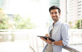 The young man using a tablet to working at out of office. The man wearing casual cloth and feeling relaxing and happy. photo