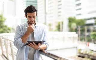 The young man using a tablet to working at out of office. The man wearing casual cloth and feeling thinking and seriously. photo