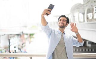 el joven se selfie consigo mismo usando el teléfono inteligente para tomar una foto y esperar a su amigo.