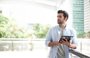 The young man using a tablet to working at out of office. The man wearing casual cloth and feeling thinking and seriously. photo