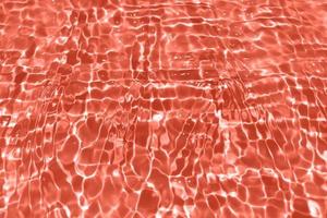 Defocus blurred transparent orange colored clear calm water surface texture with splash, bubble. Shining orange water ripple background. Surface of water in swimming pool. Orange bubble water shining. photo