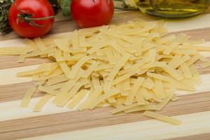 Raw pasta on wooden board and wooden background photo