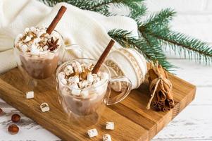 traditional Christmas drink - hot chocolate or cocoa with marshmallows against the background of a warm knitted sweater and a green branch of spruce. photo