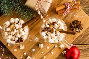 two large hooks with a chocolate drink or cocoa in a New Year's composition with balls, a gift box and cinnamon sticks. top view.