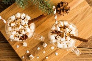 top view of a traditional chocolate Christmas drink with marshmallows in glass cropped on a wooden background. photo