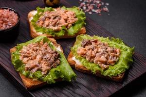 Delicious fresh sandwiches with toast, canned salmon, salad and quail eggs photo