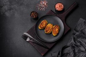 Diet vegetable cutlet from zucchini, carrot, herbs on a black plate photo