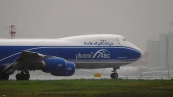 moscú, federación rusa 28 de julio de 2021 - avión de fuselaje ancho boeing 747 de airbridgecargo rodando en la pista del aeropuerto de sheremetyevo. jet jumbo de carga, vista lateral. aeródromo bajo fuertes lluvias video