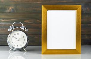 Picture mock up with golden frame and alarm clock photo